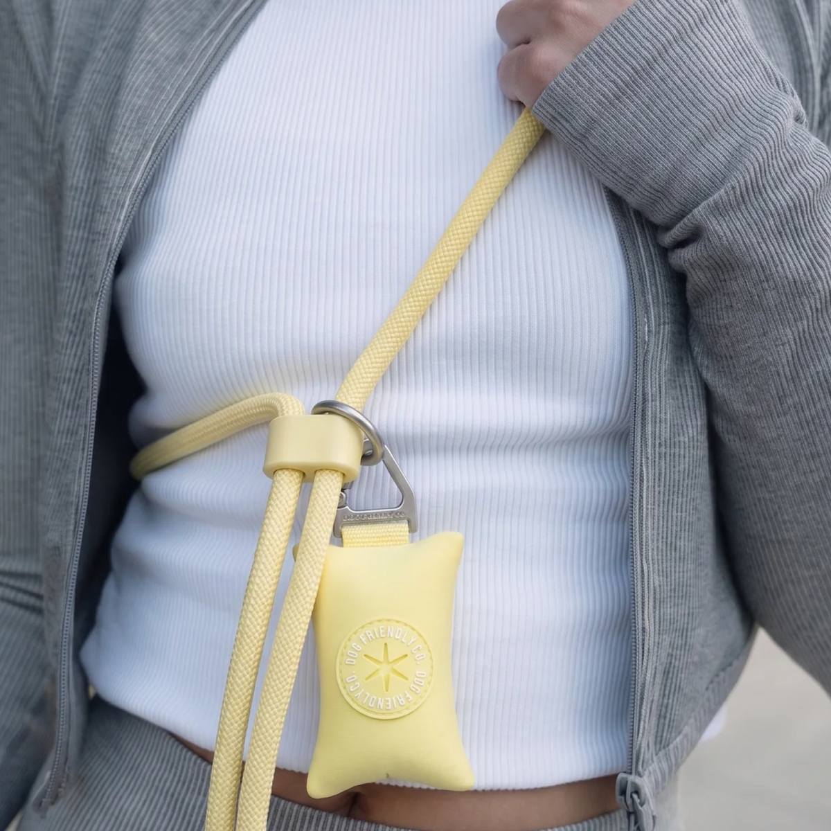 Yellow poop bag holder attached to a hands-free dog leash worn around the shoulder