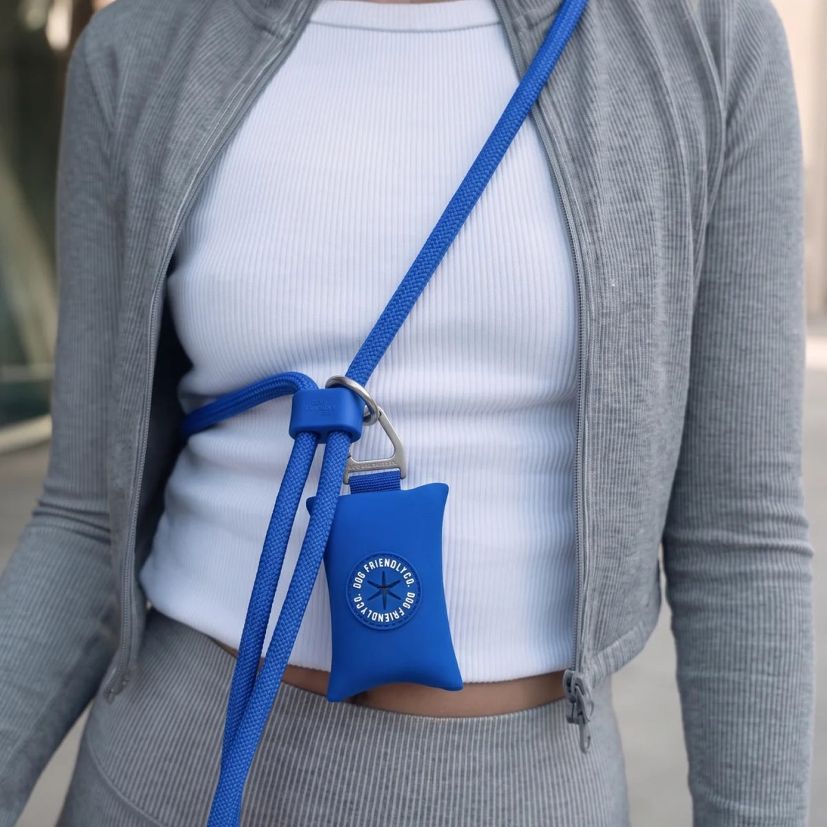 Close-up of the Classic Blue hands-free leash worn across the body with a blue poop bag holder attached to the leash.