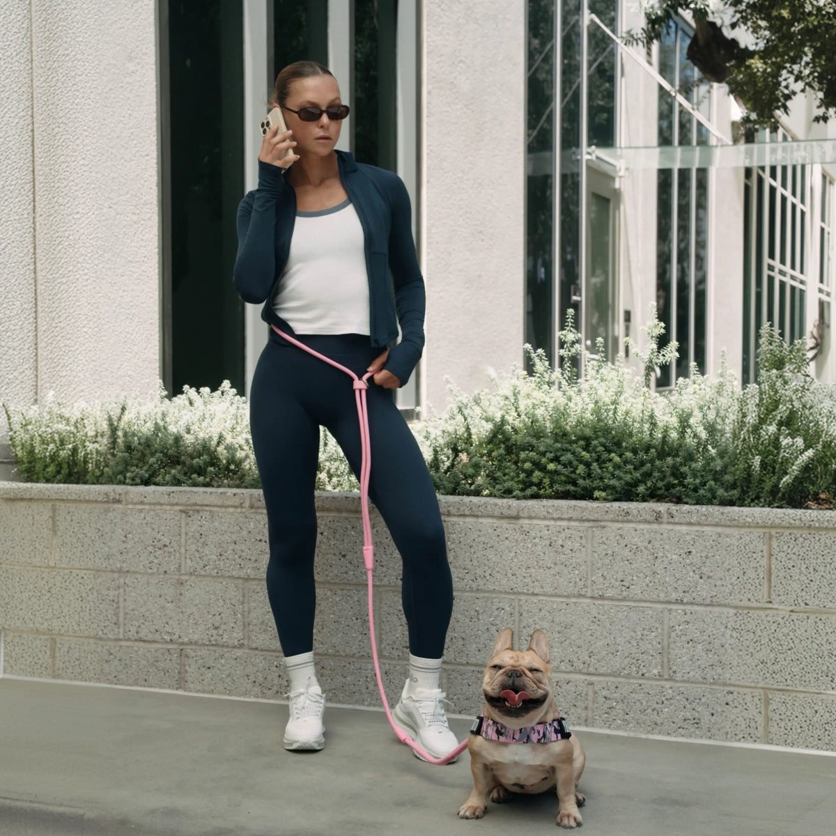 Dog owner wearing the pink hands-free leash around the waist while walking a small dog.