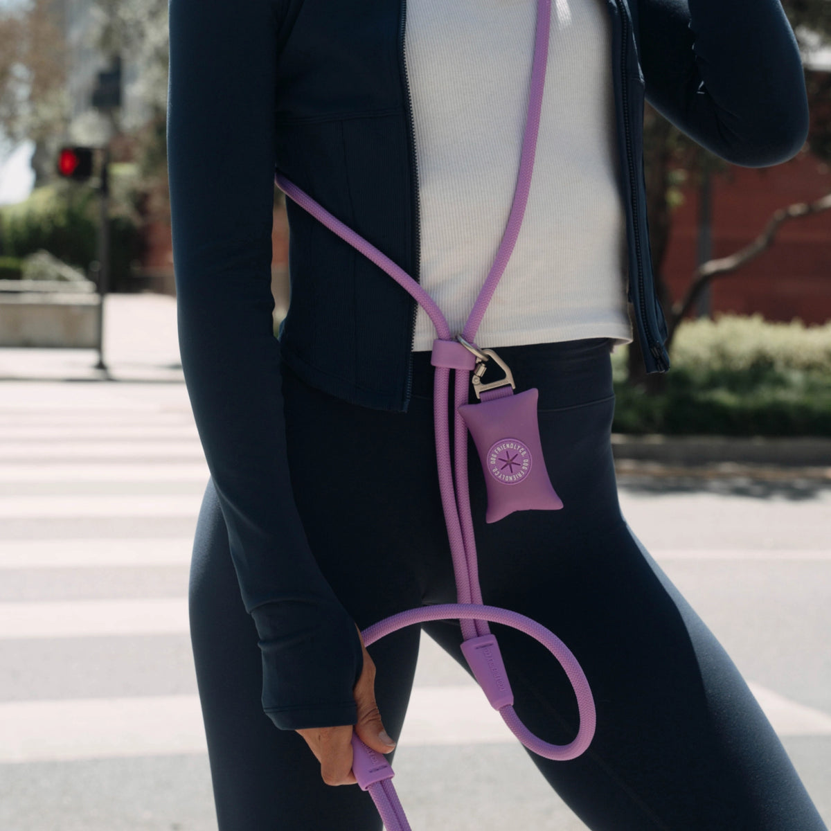 Dog owner wearing the Purple hands-free leash with a purple poop bag holder attached near the waist.